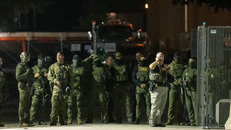 Federal law enforcement officers stand guard in the open gate of the fence built on Beach...