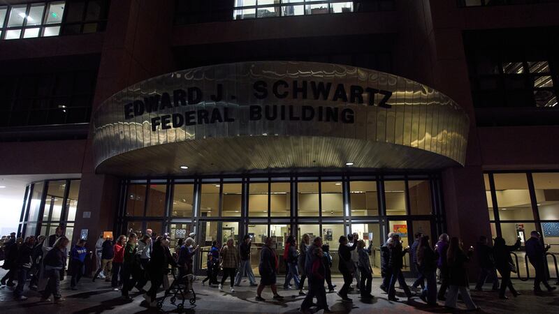 Personas se reúnen para llevar a cabo una vigilia y procesión en un tribunal federal en donde...