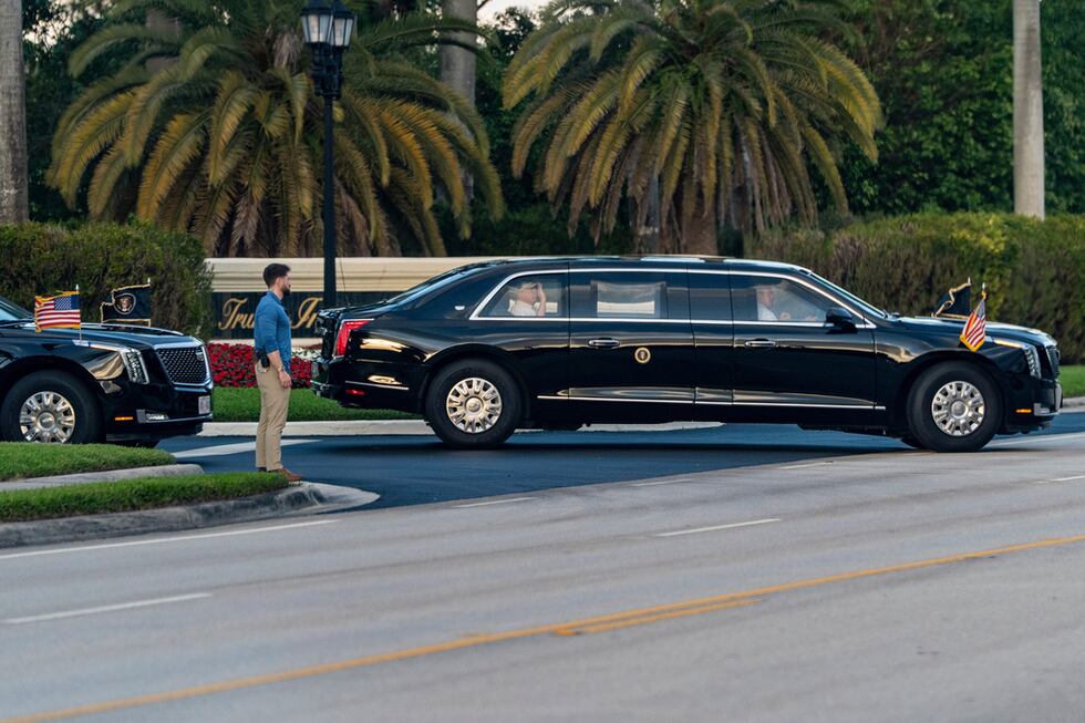 El presidente Donald Trump saluda desde su limusina al salir del Trump International Golf...